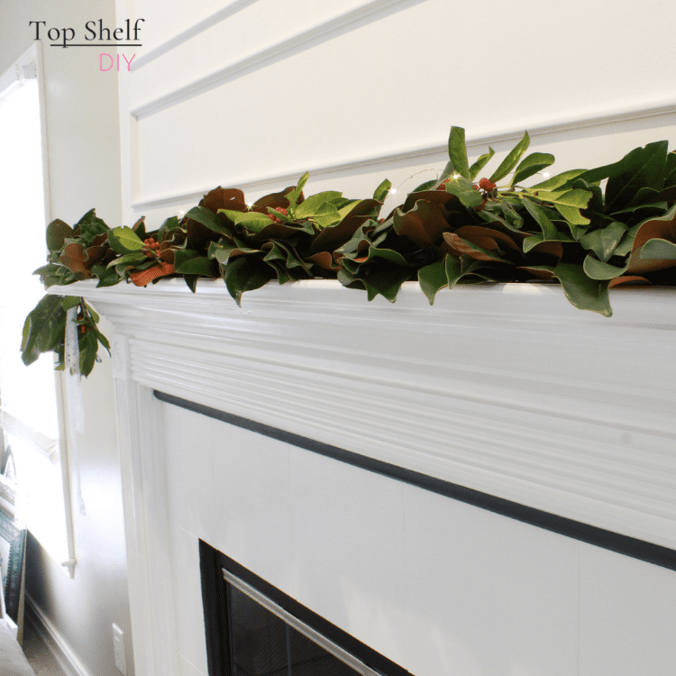 Christmas mantel with DIY magnolia garland. Here's how to update the space above the mantel with trim and white paint. #fireplacedecor #manteldecor #Marblefireplace
#Fireplacemakeover #Fireplacedesign #Modernfireplace #Seasonalmanteldécor